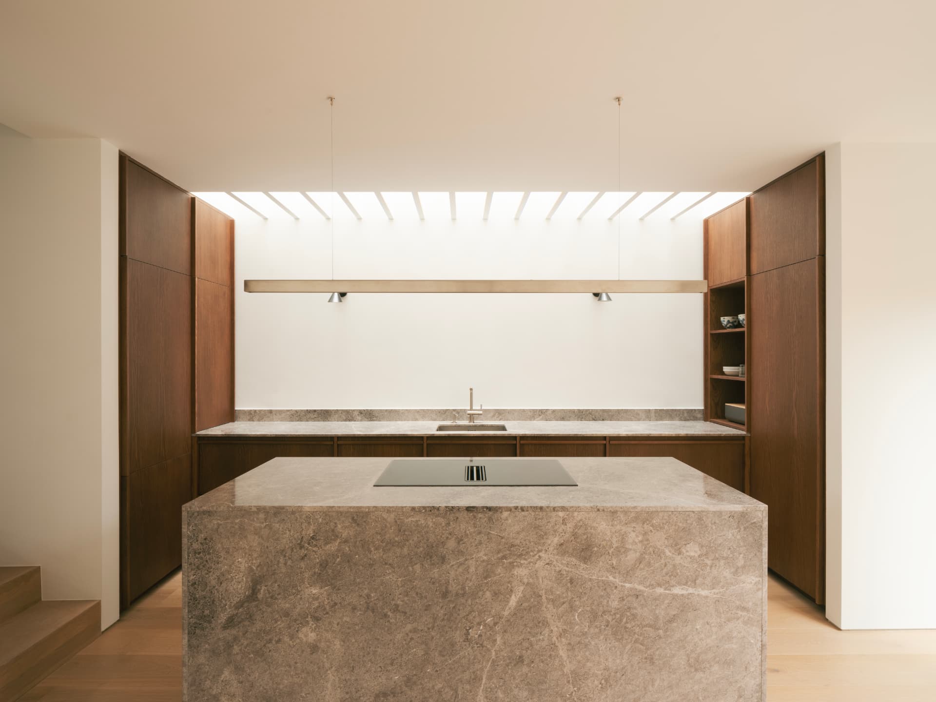 Honed stone kitchen island beneath a slatted skylight, framed by warm timber cabinetry, in a contemporary Dublin renovation
